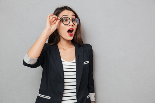 Shocked business woman in eyeglasses looking away with open mouth