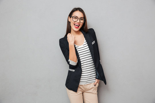 Cheerful asian business woman in eyeglasses rejoices