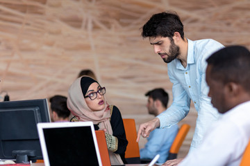 diverse college students using laptop and talking, learning exchanging ideas