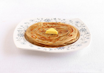 Kerala paratha, a type of Indian bread, sliced and stacked, with butter topping, made from wheat flour dough.