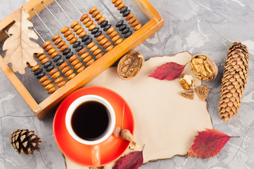 Old abacus and full cup of coffee and burnt blank paper and nut and red leaves with leaf of oak and...