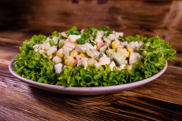 Ceramic plate with salad from crab sticks on wooden table