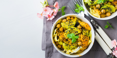Light summer salad with lettuce, kiwi, peach, chickpea and black sesame seeds, mint.