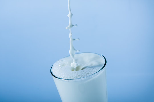 Milk glass splash with pillar on blue background