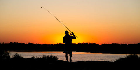 Fototapeta na wymiar Silhouette of a man with a fishing rod at sunset