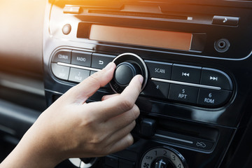 Woman turning button of radio in car