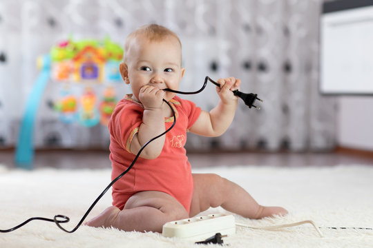 8 months age baby curious looking at electronic plug