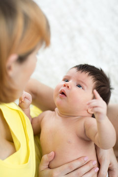 Funny newborn baby and mother looking each at other