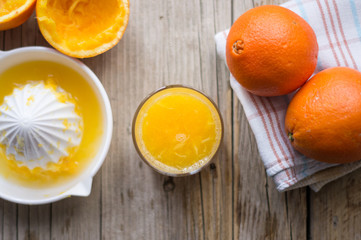 Fresh orange juice with squeezer and oranges on a side