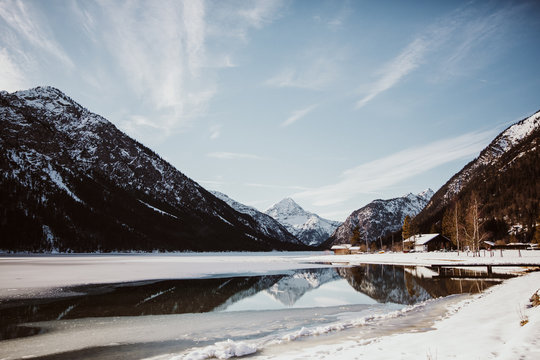 Scenic view of mountains reflected in water during winter