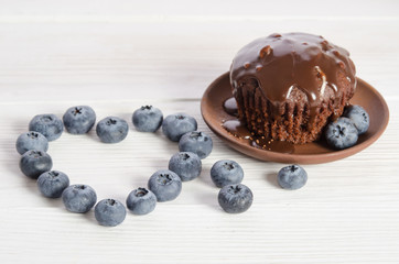 Frame- heart from blueberry  and cupcake on wooden table   top view
