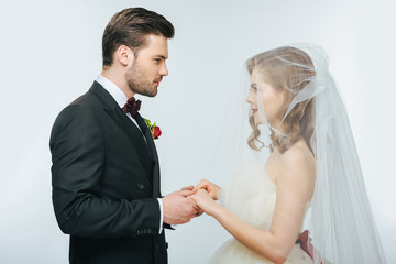 side view of beautiful wedding couple holding hands and looking at each other