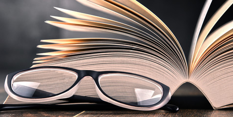 Composition with open book and glasses on the table