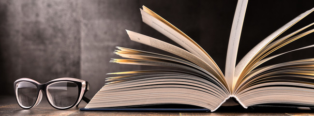 Fototapeta premium Skład z otwartą książką i szklankami na stole