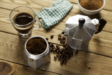 Italian coffee maker with napkin and cup of coffee on wood table