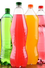 Plastic bottles of assorted carbonated soft drinks over white