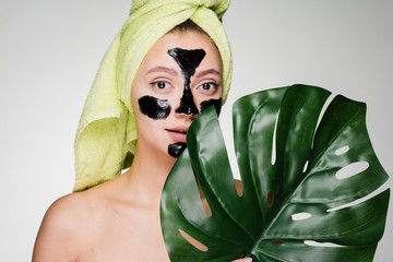 a lovely young girl with a green towel on her head applied a black cleansing mask to the problem...