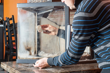 Man wipes the dirty glass of fireplace