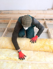 Work composed of mineral wool insulation in the floor, floor heating insulation , warm house, eco-friendly insulation, a builder at work