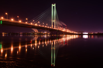Night city. Beautiful glowing bridge over the river