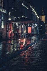 Cinematic street photography shot with colorful lights and reflections on pavement during the night in Kaunas, Lithuania