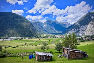 alpine peaks and valley under a blue cloudy sky with wood stack in the foreground in Nassereith,...