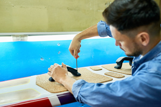Back view portrait of handsome modern man  making custom  surfing board placing pads on it and screwing in handles