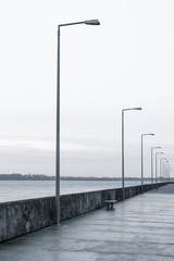 Row of lanterns at a grey gloomy ocean pier - concept loneliness depression
