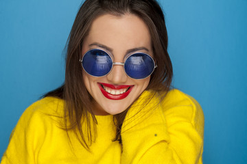 Naklejka premium beautiful smiling woman with blue sunglasses and yellow blouse