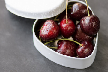 Black cherries in white box on chalk black background. Tasty, healthy, summer berry. Red Cherries. Close up view