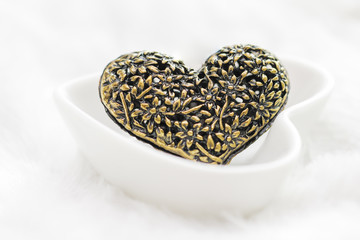 Black silver heart pendant on white background with feathers