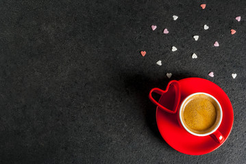Valentine's day concept, coffee mug and sweet heart shaped sprinkles, black background, copy space  top view