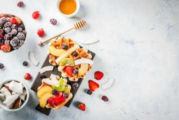 Breakfast. Homemade fresh Belgian soft wafers with honey, fruits, nuts, berries - peach, blackberries, raspberries, strawberries, coconut, cashews, strawberries, mint. Light table. Copy space top view