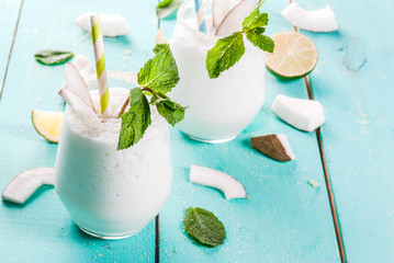 Summer refreshment drinks, cocktails. Frozen coconut mojito with lime and mint. Pina colada. On a light blue green wooden table with ingredients. Copy space - obrazy, fototapety, plakaty