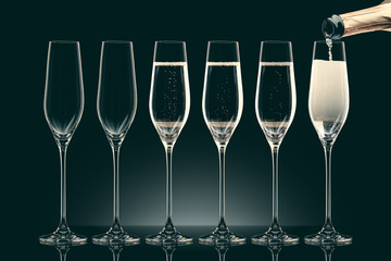 pouring champagne from bottle into six transparent glasses on black