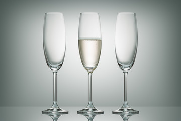two empty glasses and one glass with champagne on white