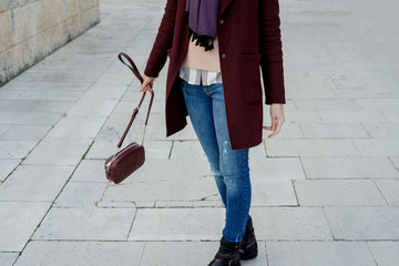 Trendy Young woman in a stylish burgundy coat in the spring walking outdoors.