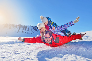 happy young family playing in fresh snow at beautiful sunny winter day outdoor in nature