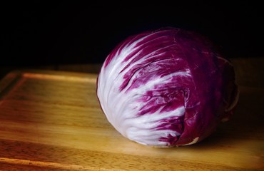 Head of purple radicchio lettuce on cutting board © Philip