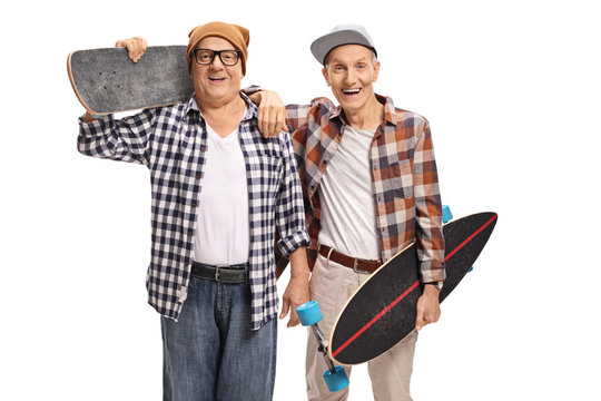 Two elderly skaters with longboards looking at the camera and smiling