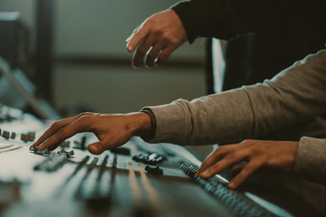cropped shot of men using analog graphic equalizer at recording studio