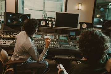 back view of sound producers looking at blank monitor at recording studio