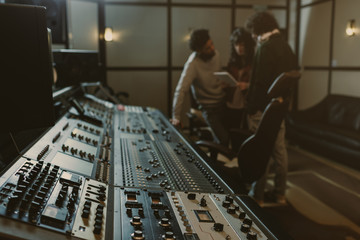 blurred group of musicians spending time at recording studio with graphic equalizer
