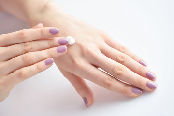 Obraz na płótnie Canvas Women's hands with pink manicure applying cream. The concept of skin care.