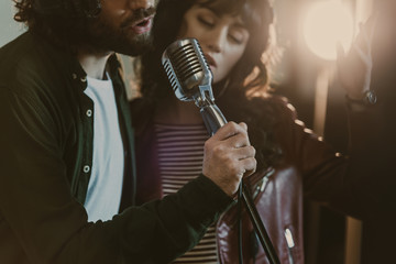 close-up shot of young couple performing song with vintage microphone
