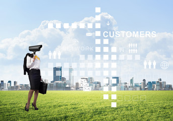 Camera headed woman standing on green grass against modern cityscape