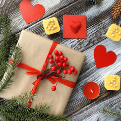 Valentine's Day composition with romantic decorations: gift box, candles, sweets and red hearts on wooden vintage background. Winter Flat Lay, top view. Love or congratulation concept. 