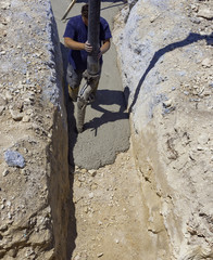 building construction worker pouring cement or concrete with pump tube