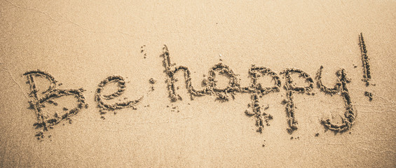 Be Happy text written on the sand