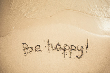Be Happy text written on the sand